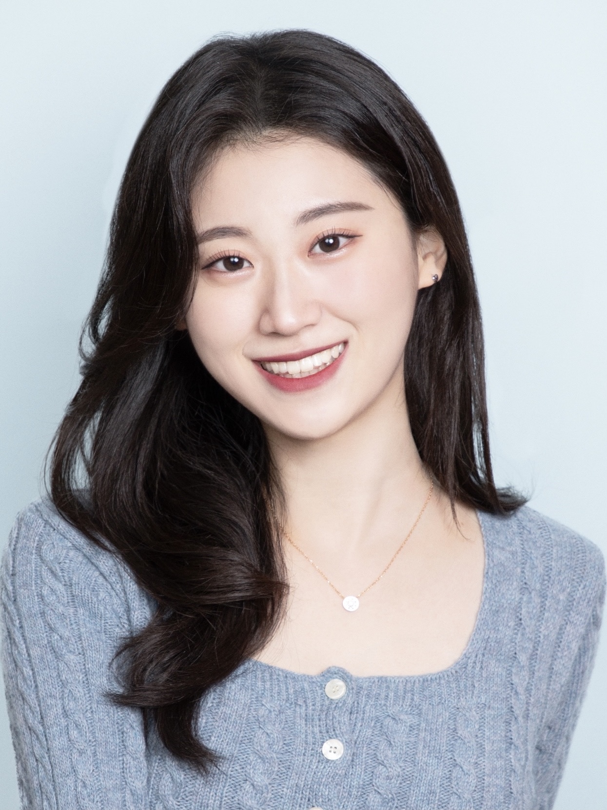 Selin Choi with long hair, wearing a blue cardigan